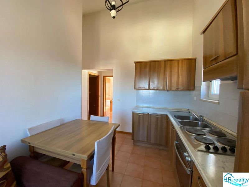 A kitchen in a holiday apartment with wooden cabinets and a dining table.