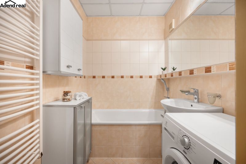 A bathroom in a 3-room apartment with a bathtub, washing machine, and cabinet.
