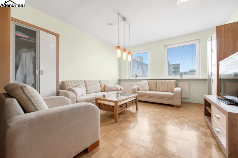 Living room in a 3-room apartment with a sectional sofa and a floor with a wood decor.