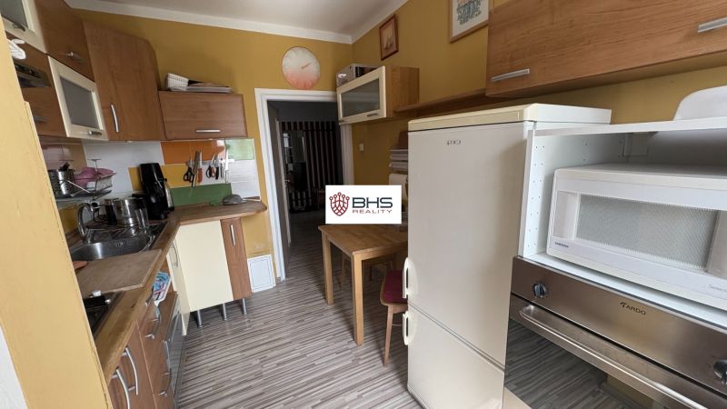 A kitchen in a 2-room apartment with yellow walls and a wooden decor floor.
