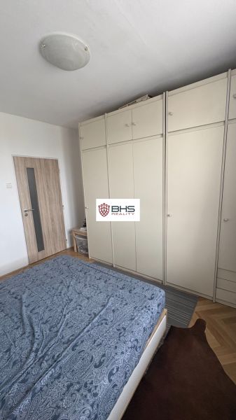 A bedroom with a bed, wardrobe, and wooden decor flooring in a two-room apartment.