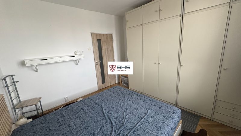 Bedroom with a large wardrobe and wooden decor flooring in a 2-room apartment.