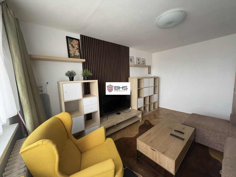 Living room in a 2-room apartment with a wooden decor floor and a yellow armchair.