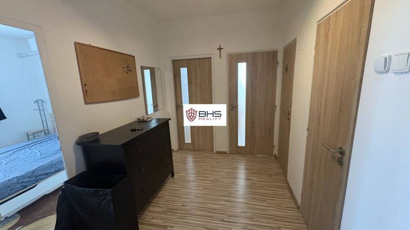 A hallway with wooden doors and a chest of drawers in a 2-room apartment, flooring with a wooden decor.