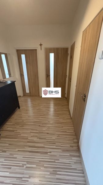 A hallway with multiple doors and a wooden decor floor in a 2-room apartment.