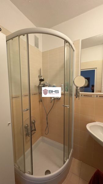 Bathroom with a shower in a 2-room apartment, cream-colored tiles.