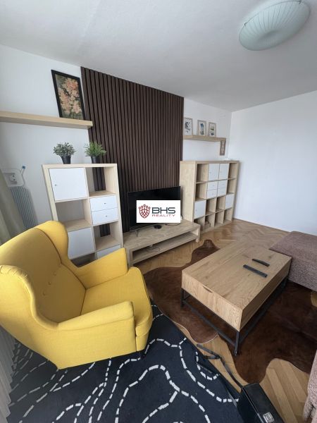 Living room with wood-patterned flooring, a yellow armchair, and a wooden coffee table.