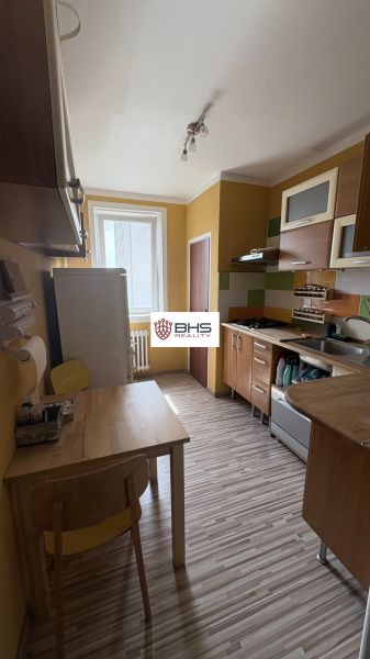 A kitchen with yellow walls, wooden furniture, and a floor with a wooden decor in a 2-room apartment.