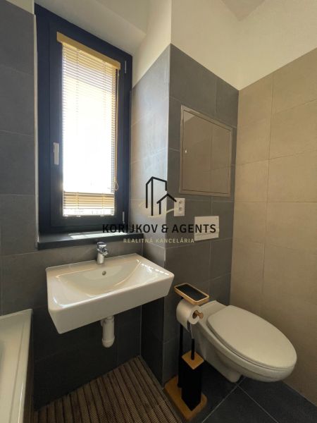 A bathroom with a sink, toilet, and window in a 2-room apartment.
