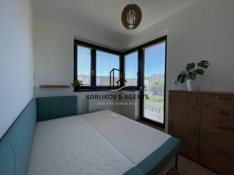 Bedroom in a 2-room apartment with a bed and a wooden dresser, the room is bright.