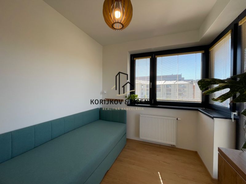 A room with a sofa, windows with blinds, and a floor with a wood decor in a 2-room apartment.