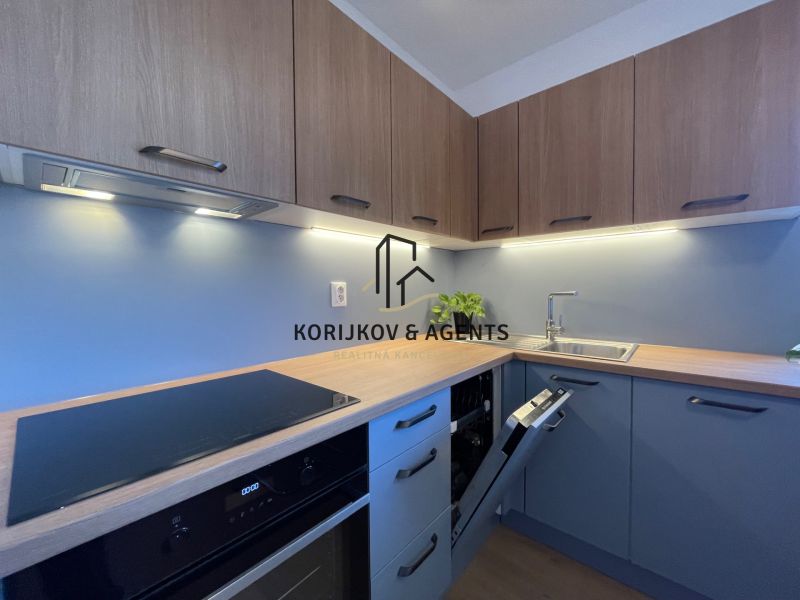 A modern kitchen in a 2-room apartment with a wooden decor floor and blue cabinets.