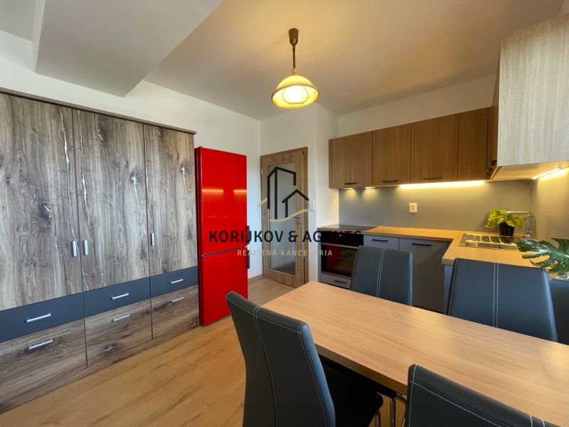 A kitchen in a 2-room apartment with cabinets featuring a wooden decor and a red refrigerator.