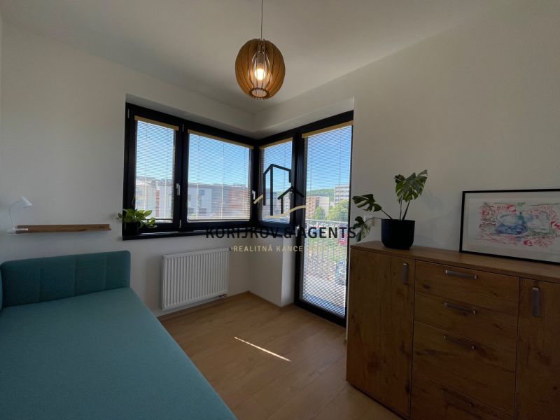 A room in a 2-room apartment with a bed, a dresser, and a floor with a wood decor.