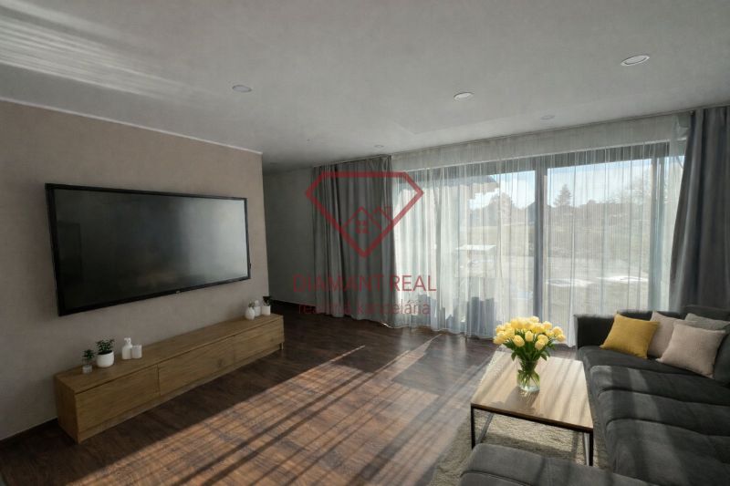 Living room in a family house with a large television, sofa, and wooden decor flooring.