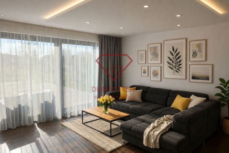 Living room of a family house with a sofa, decorative paintings, and a wooden-patterned floor.