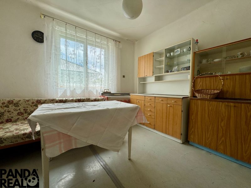 A room in a family house with a floral sofa, table, and wooden furniture.