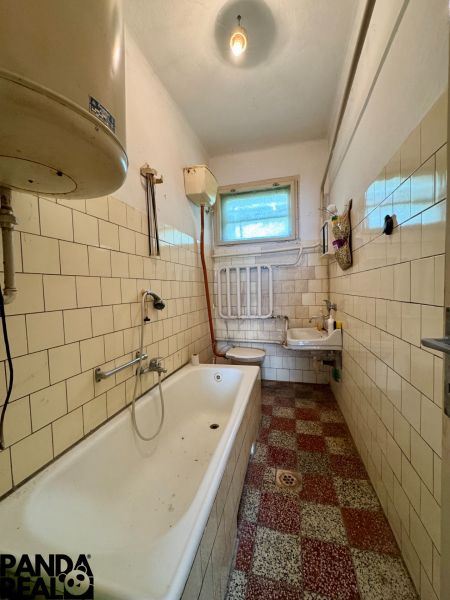 Bathroom in a family house with a bathtub, sink, and tiles.