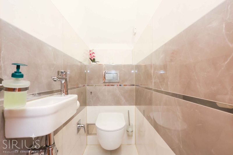 Bathroom in a family house with ceramic tiles and a toilet.