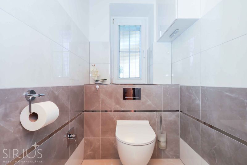 A minimalist bathroom in a family house with tiles and a window.