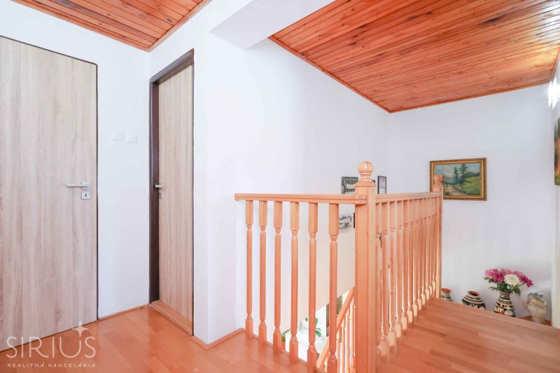 A staircase with a wooden railing and a floor with a wooden decor in a family house.