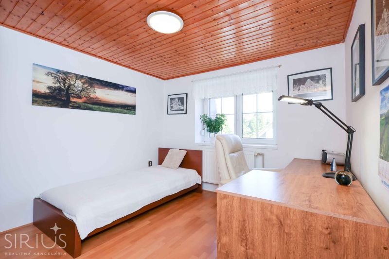 A room in a family house with a table, a chair, and a bunk bed. The floor has a wood decor.