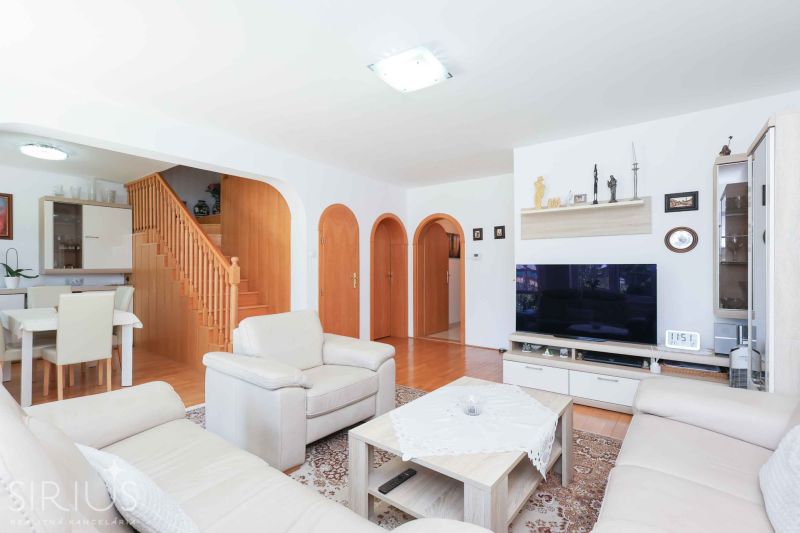 Living room in a family house with cream furniture and a wooden decor floor.