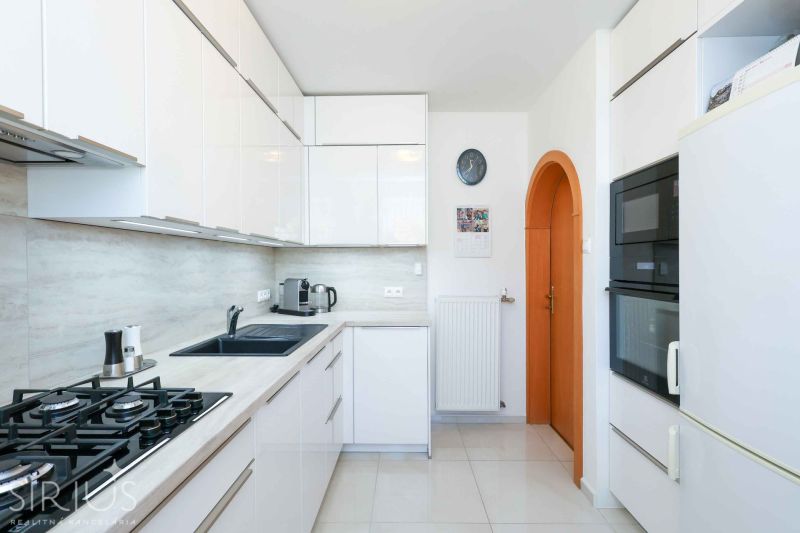 A kitchen in a family house with white cabinets and appliances, and a floor with a wooden decor.