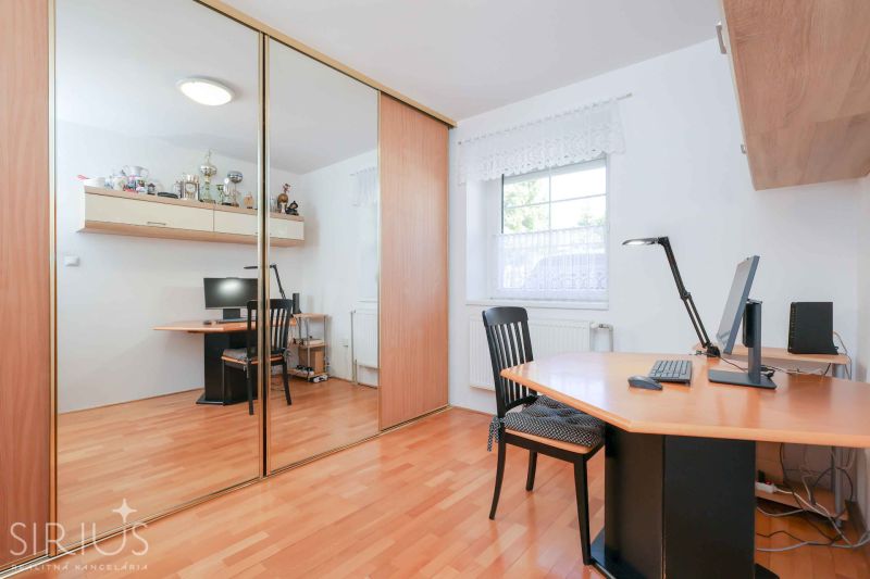 A study in a family house with a wooden decor floor and a large mirrored wardrobe.