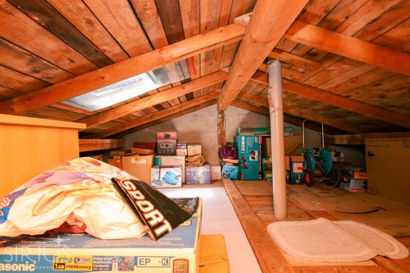 Attic space with stored boxes and wooden paneling in a family house.