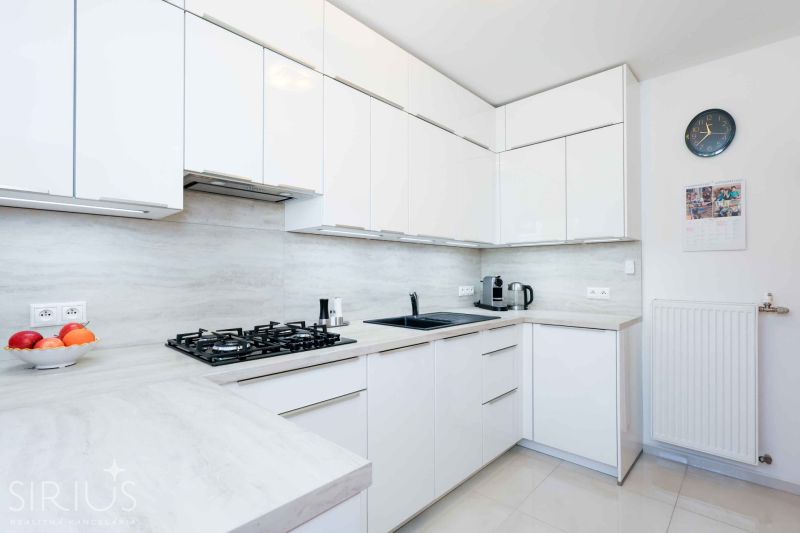 A kitchen in a family house with a counter, appliances, and white cabinets.