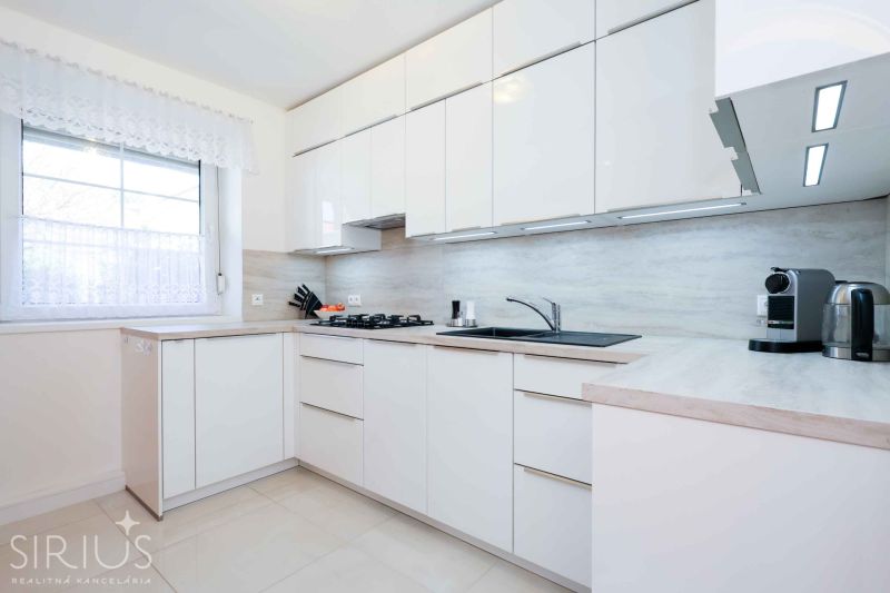 A kitchen unit in a family house with white cabinets and appliances on the countertop.