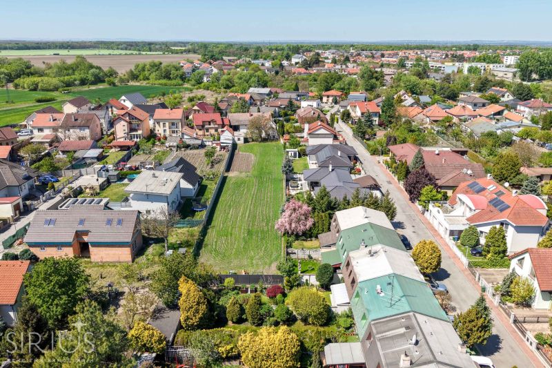 An aerial photograph shows family houses on Hollého Street in Stupava surrounded by greenery.