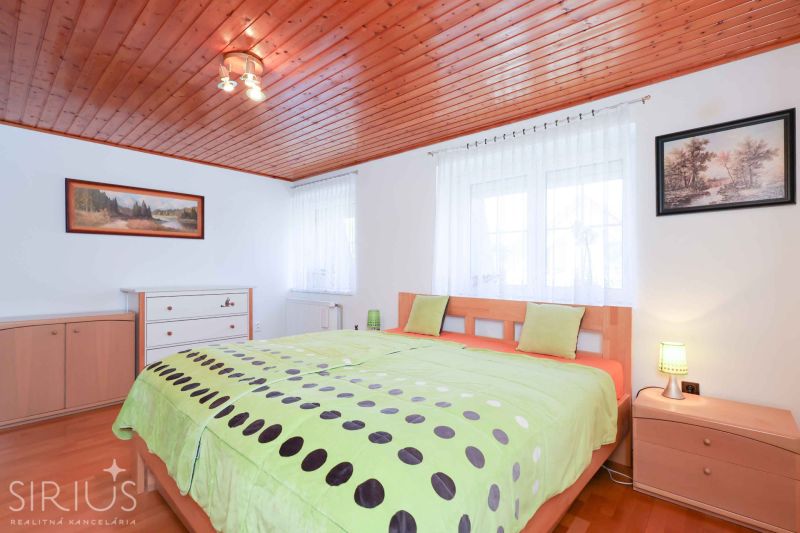 A bedroom in a family house with a wooden ceiling, decorative paintings, and a floor with a wooden decor.