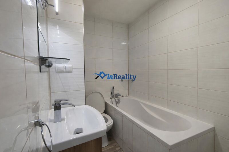 Bathroom with shower and bathtub in a studio apartment, bright ceramic tiles.