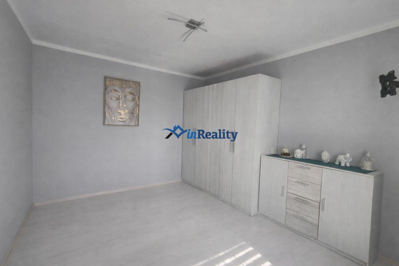 A bright room in a one-bedroom apartment with a wardrobe and decorations on the dresser.