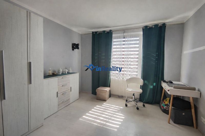 A room in a one-room apartment, light floor with wood decor, chair and table.