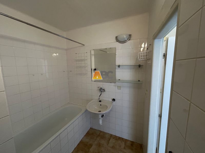 A bathroom with a bathtub in a 2-room apartment with tiled walls.