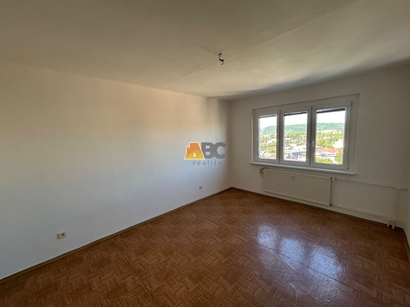 A spacious room with a wood-patterned floor in a 2-room apartment.