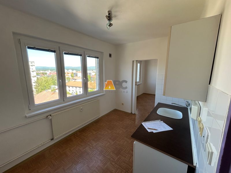 A kitchen in a 2-room apartment with light walls and a floor with a wood decor.