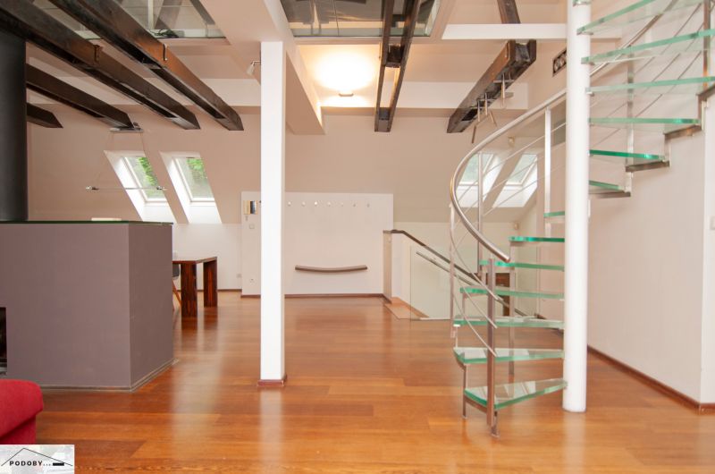 A spacious attic with a spiral staircase and a wooden decor floor in a 3-room apartment.