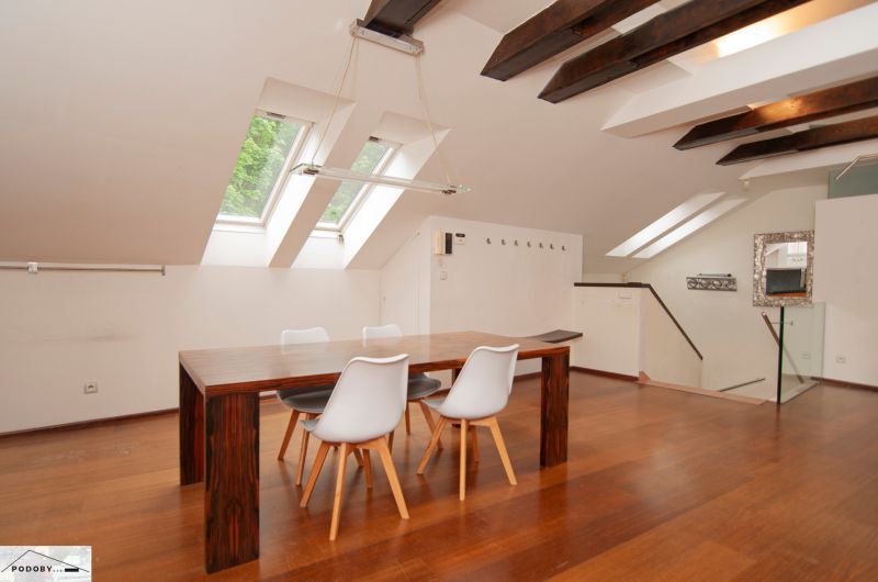 A bright dining room in a three-room apartment with wood-patterned flooring and skylights.