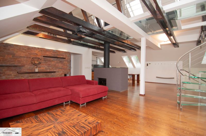 Attic living space with a large red sofa and wood-patterned flooring in a 3-room apartment.