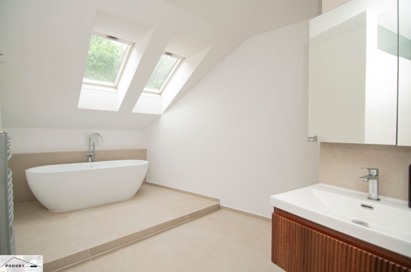 A bathroom with skylights, a freestanding bathtub, and a sink in a three-room apartment.