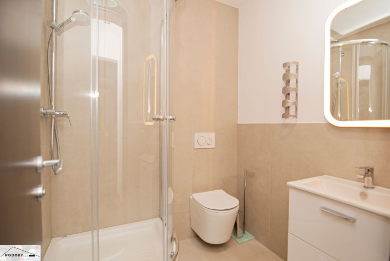 A bathroom in a 3-room apartment with a shower and a toilet.