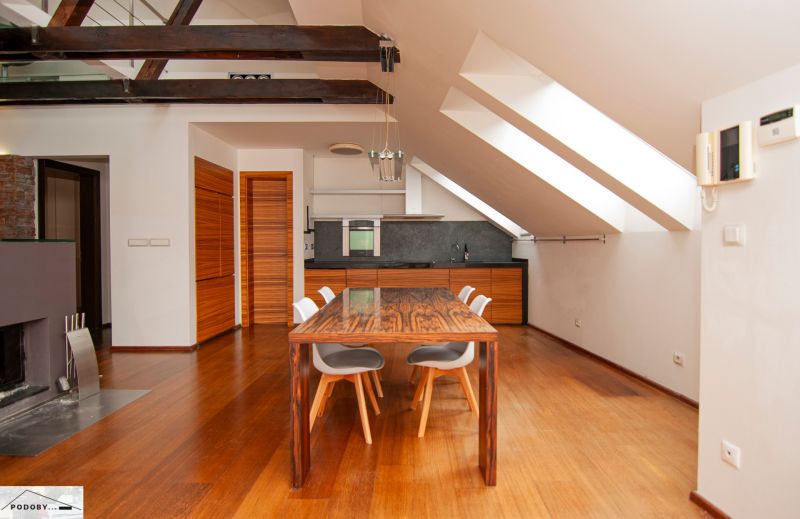 Dining area in a 3-room apartment with a wood-patterned floor and wooden beams.