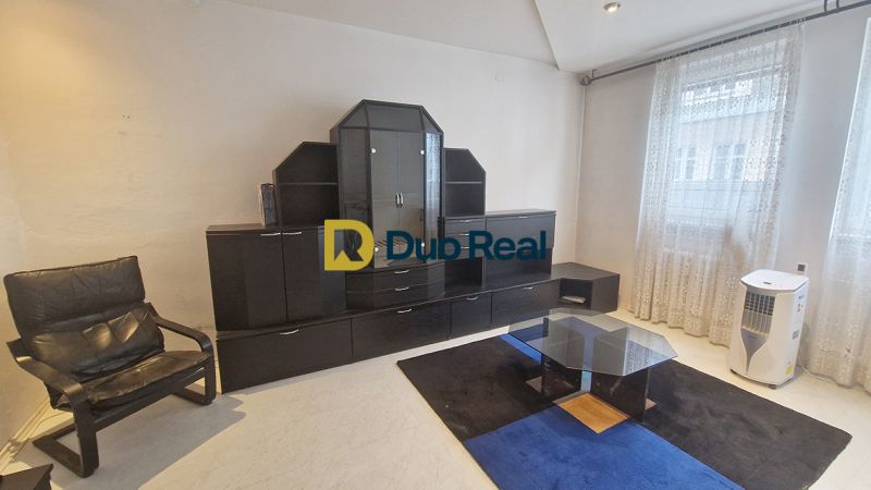 Living room with a sofa, glass table, and dark wall unit in a 3-room apartment.