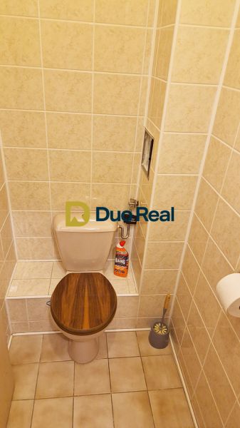 A toilet with tiles and a toilet brush in a 3-room apartment.
