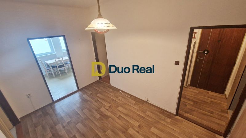 A room with a wooden decor floor, entrance door, and dining area in a 3-room apartment.