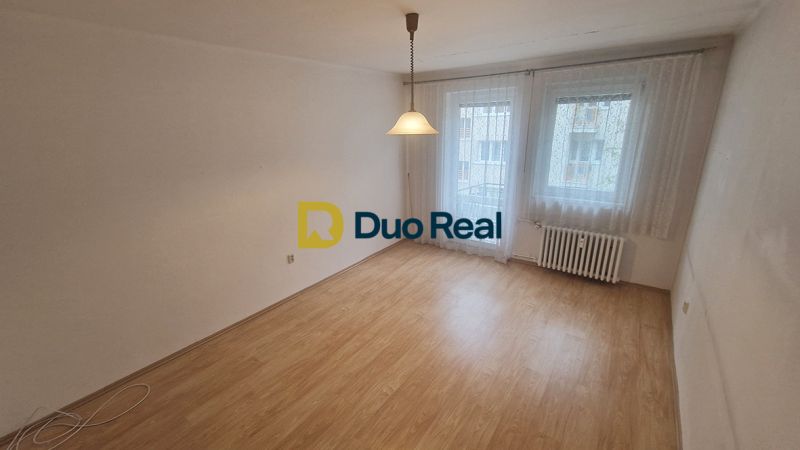 A room in a 3-room apartment with a floor featuring a wooden decor and hanging curtains.